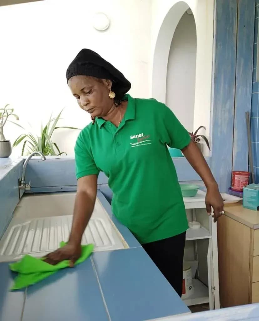 Une femme en chemise verte nettoie un comptoir de cuisine
