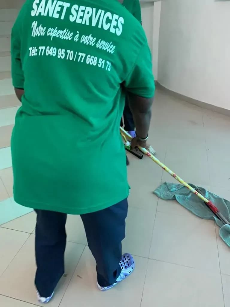 Une personne portant une chemise verte sur laquelle est écrit « Sanet Services »
